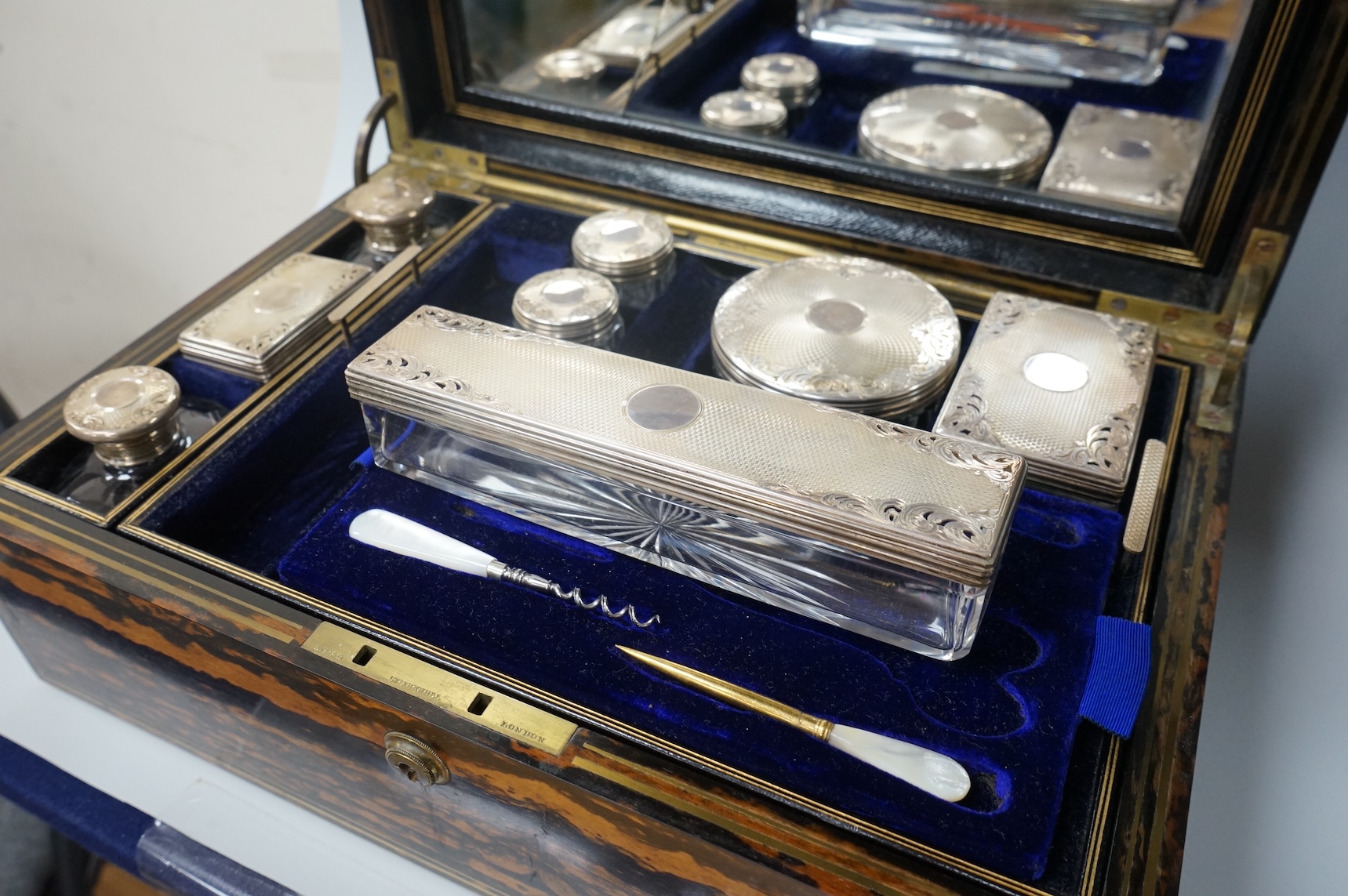 A Victorian brass mounted coromandel wood toilet box by Lund, 57 Cornhill, London, containing eight silver mounted glass toilet jars, six hallmarked for Thomas Johnson I, London, 1865 and three associated? mother of pear
